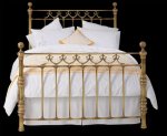 Brass bedspread with ornate metal headboard and footboard.